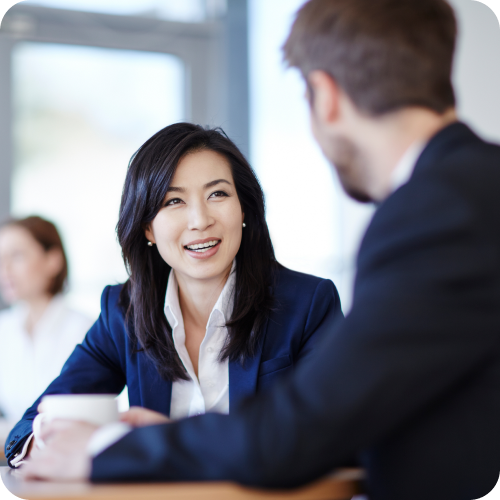 a woman and a man in suits discussing business over a cup of coffee